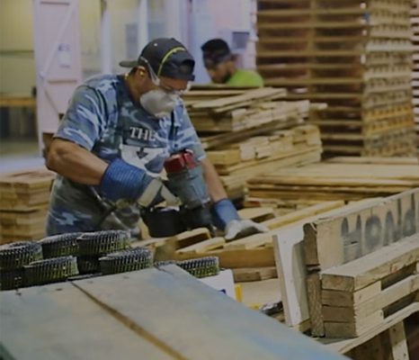 Man working in factory holding nail gun for pallet repair